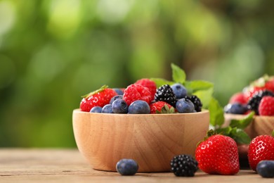 Photo of Different fresh ripe berries and mint on table outdoors, space for text