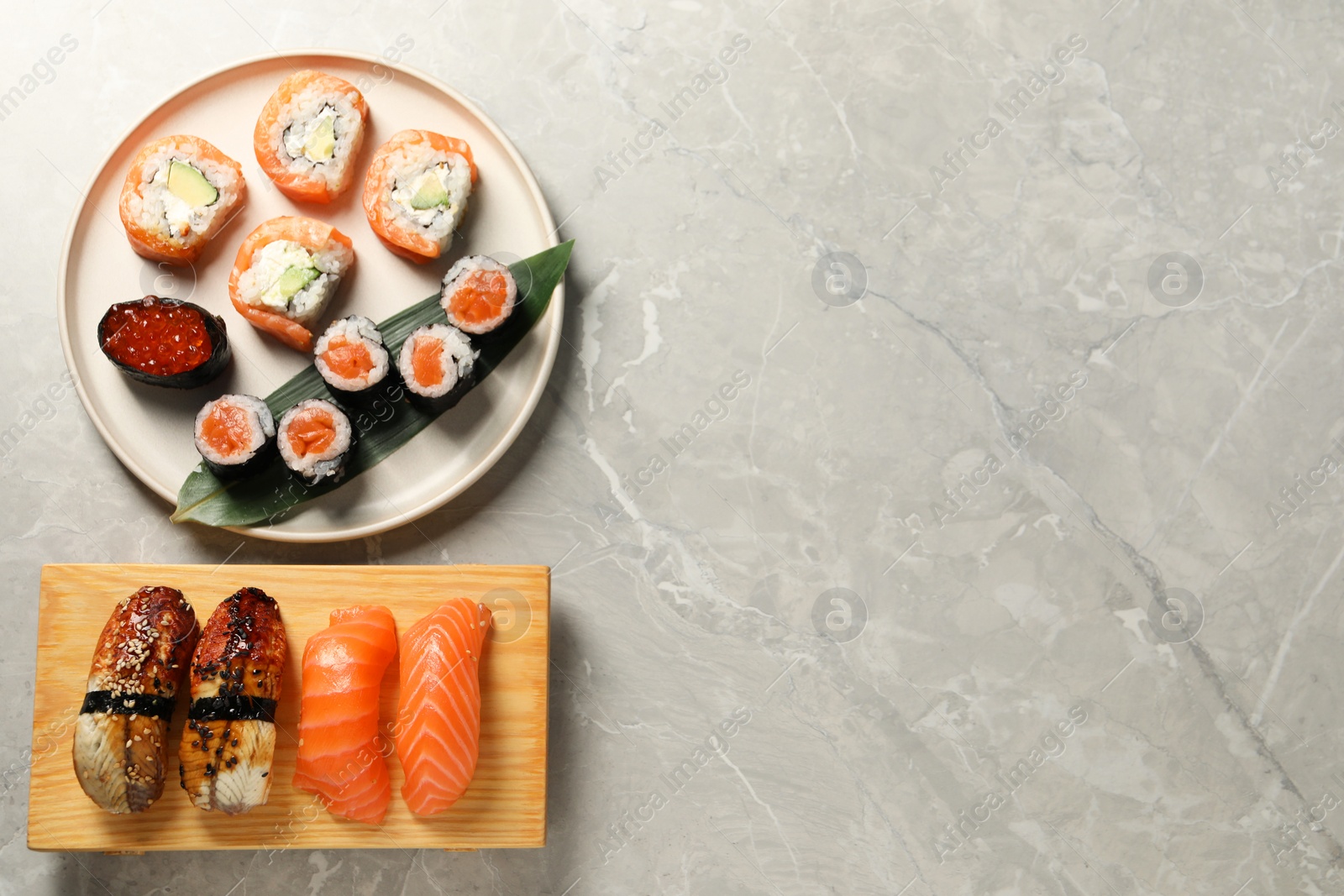 Photo of Delicious sushi rolls on light grey marble table, flat lay. Space for text