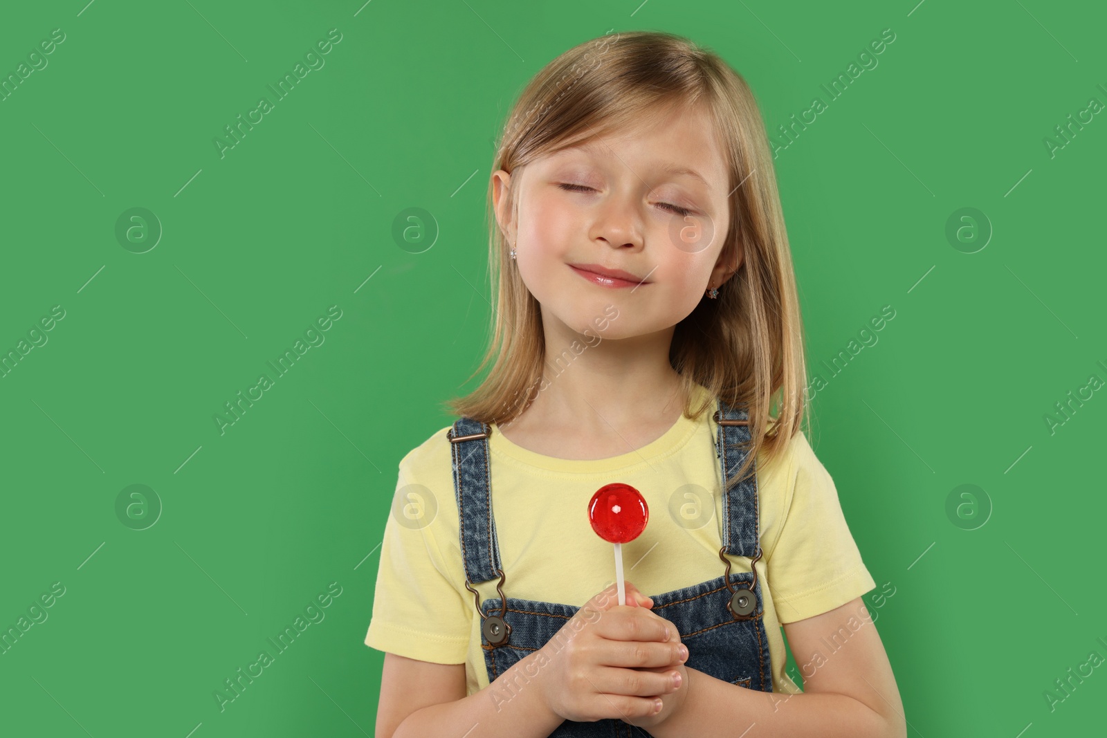 Photo of Portrait of cute girl with lollipop on green background, space for text