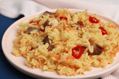 Delicious pilaf with meat on blue table, closeup