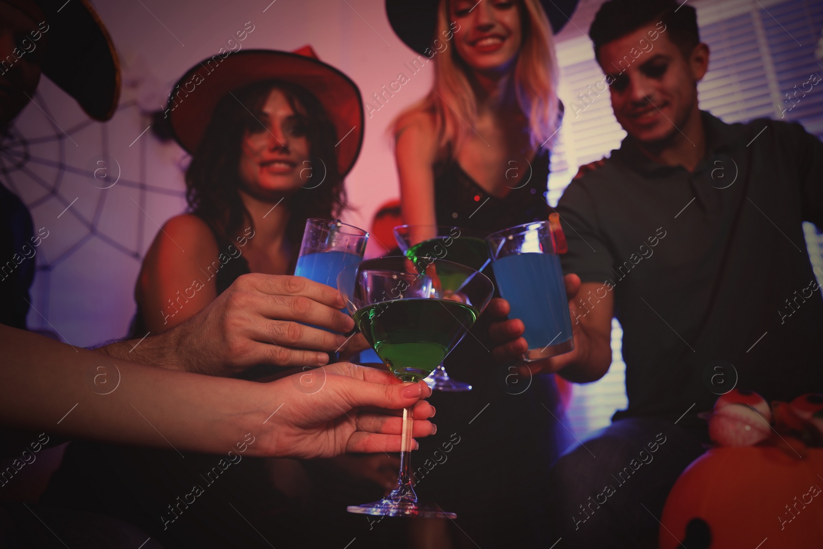 Photo of Group of friends toasting with cocktails at Halloween party indoors