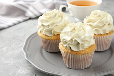 Photo of Tasty cupcakes with vanilla cream on grey table, closeup