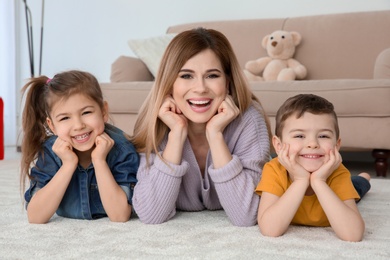 Photo of Nanny and little children lying on floor at home