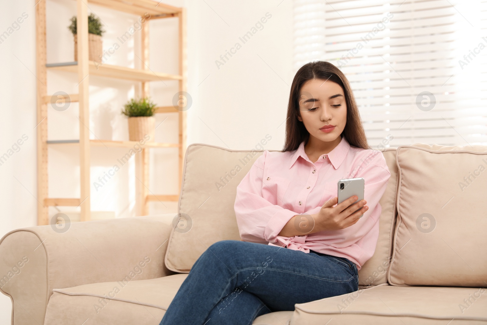 Photo of Young woman addicted to smartphone at home