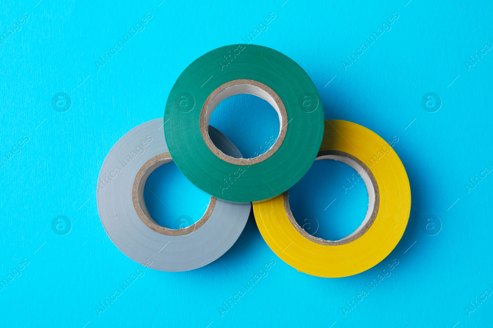 Photo of Colorful insulating tapes on light blue background, flat lay