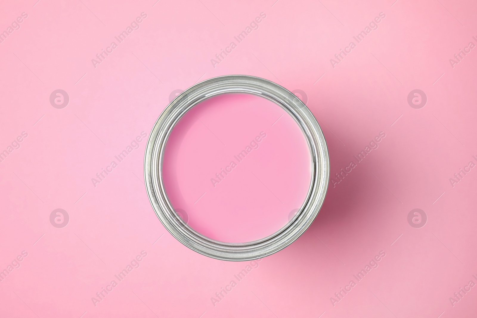 Photo of Open can of paint on pink background, top view