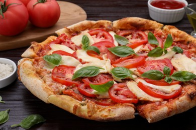 Photo of Delicious Caprese pizza on black wooden table, closeup