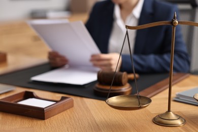 Photo of Notary reading document at table in office, focus on scales