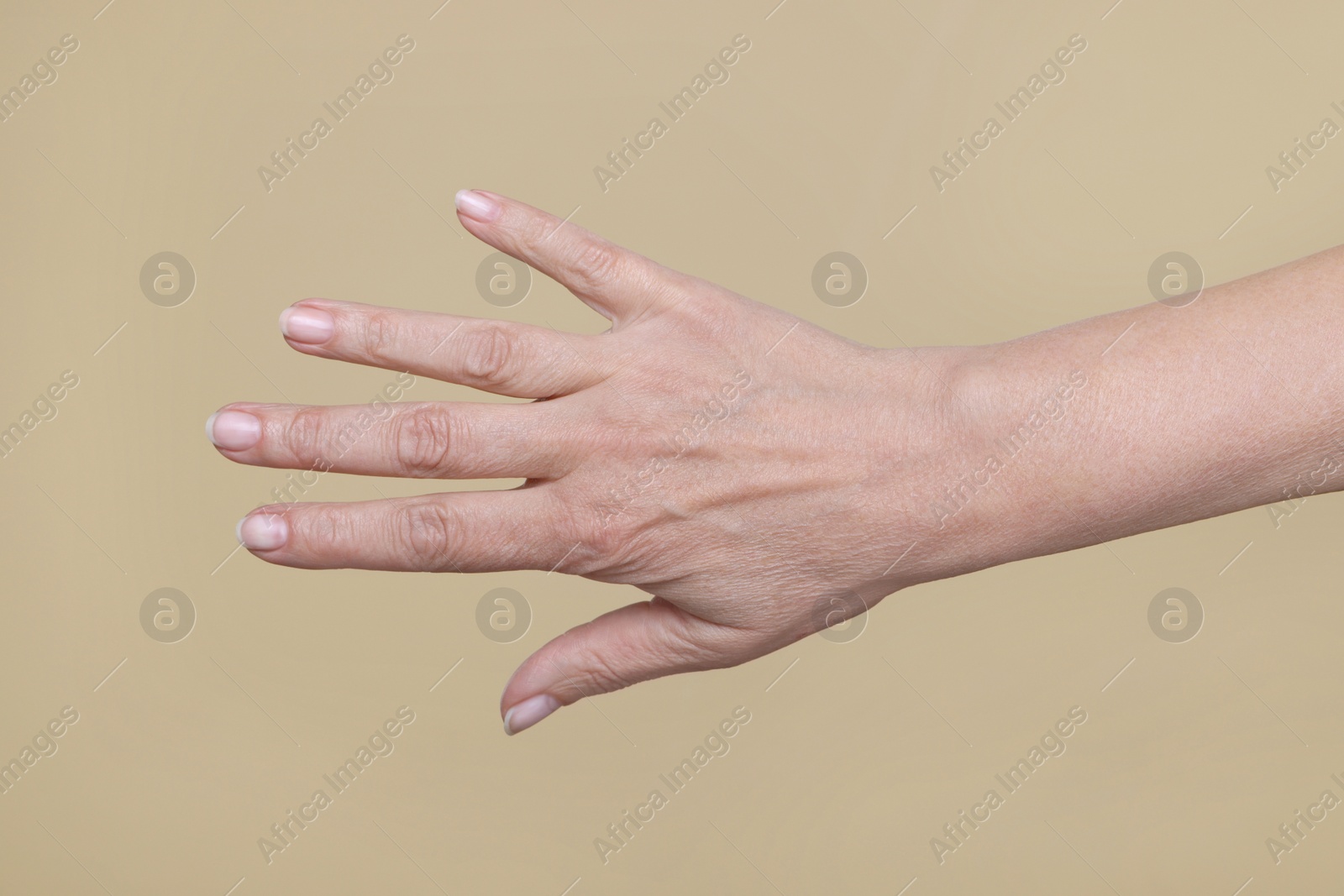 Photo of Closeup of woman's hand with aging skin on beige background. Rejuvenation treatment