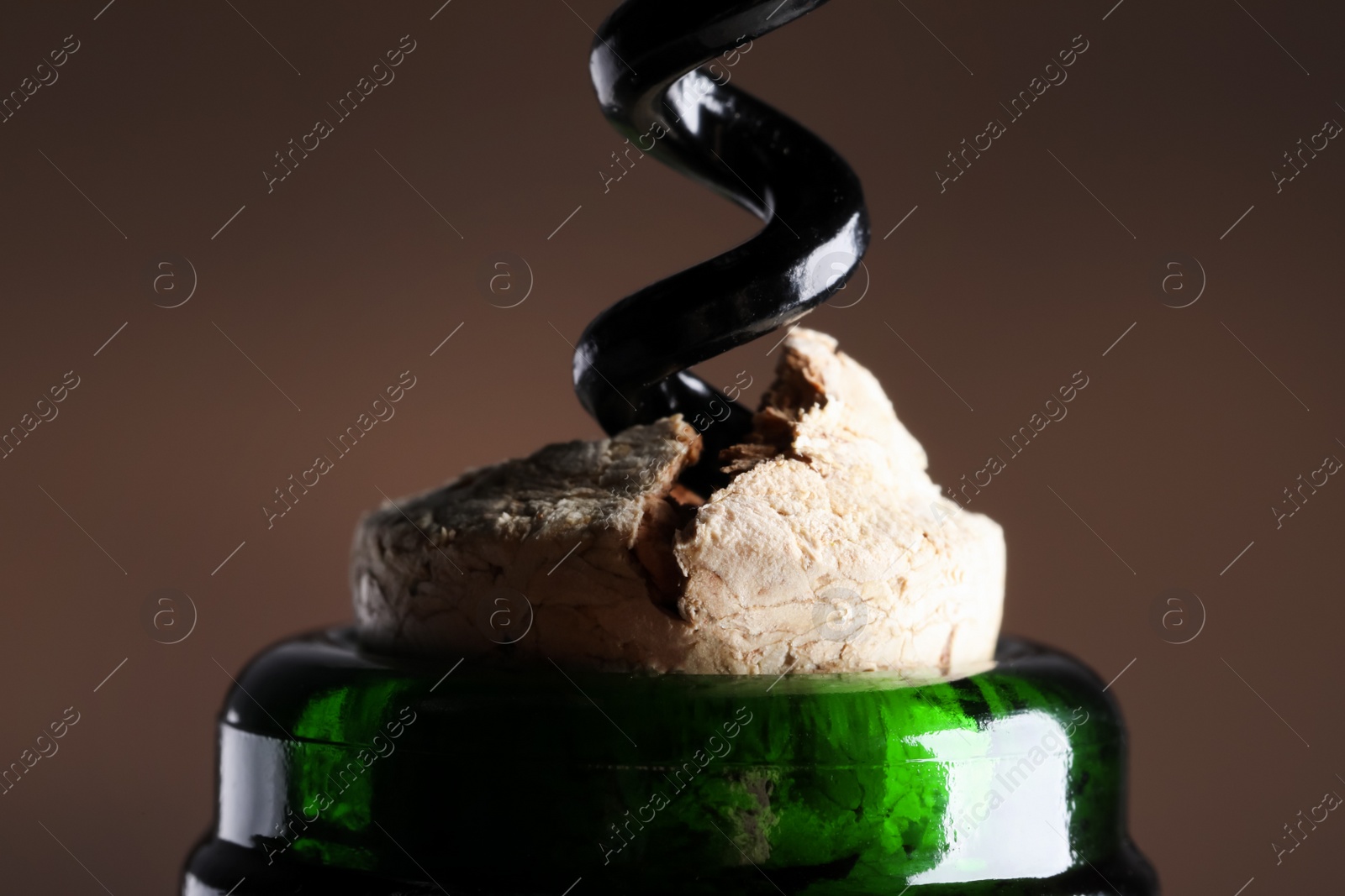 Photo of Opening wine bottle with corkscrew on dark background, closeup