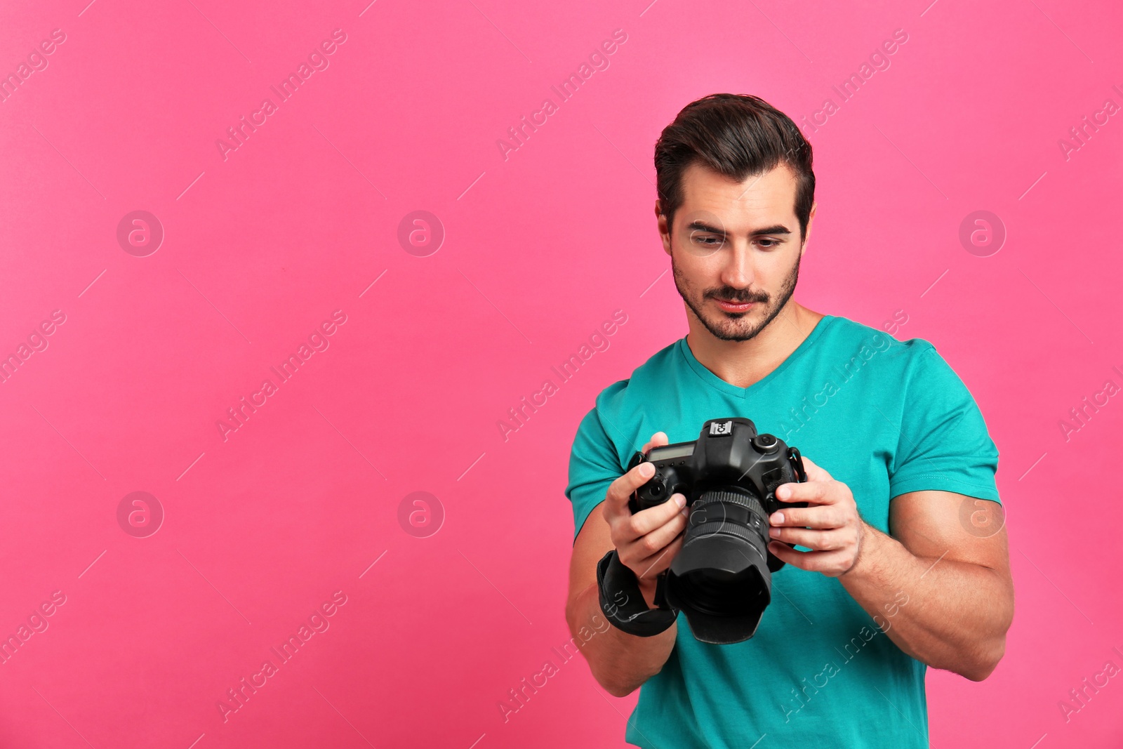 Photo of Young photographer with professional camera on pink background. Space for text