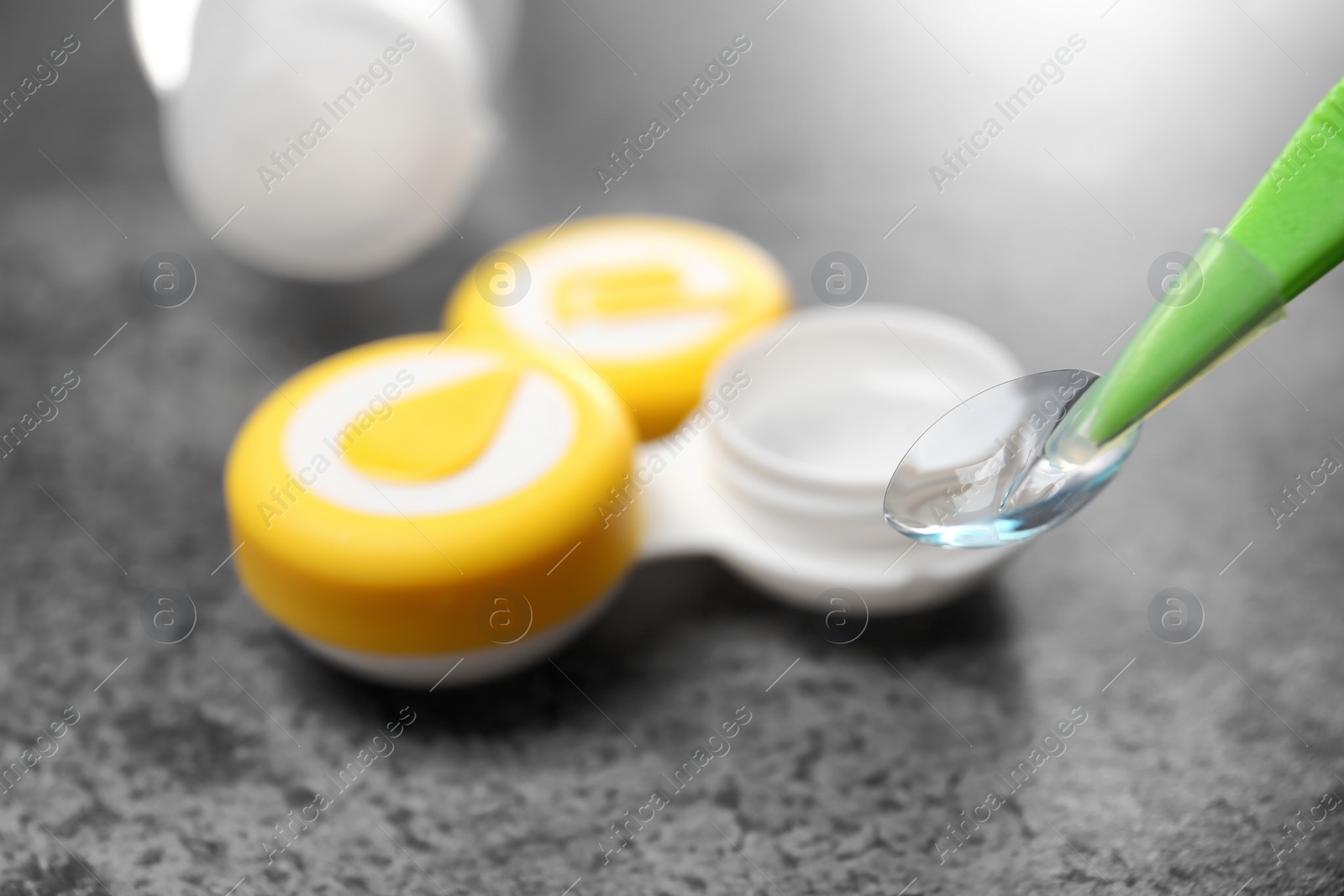 Photo of Taking contact lens from case on grey background, closeup