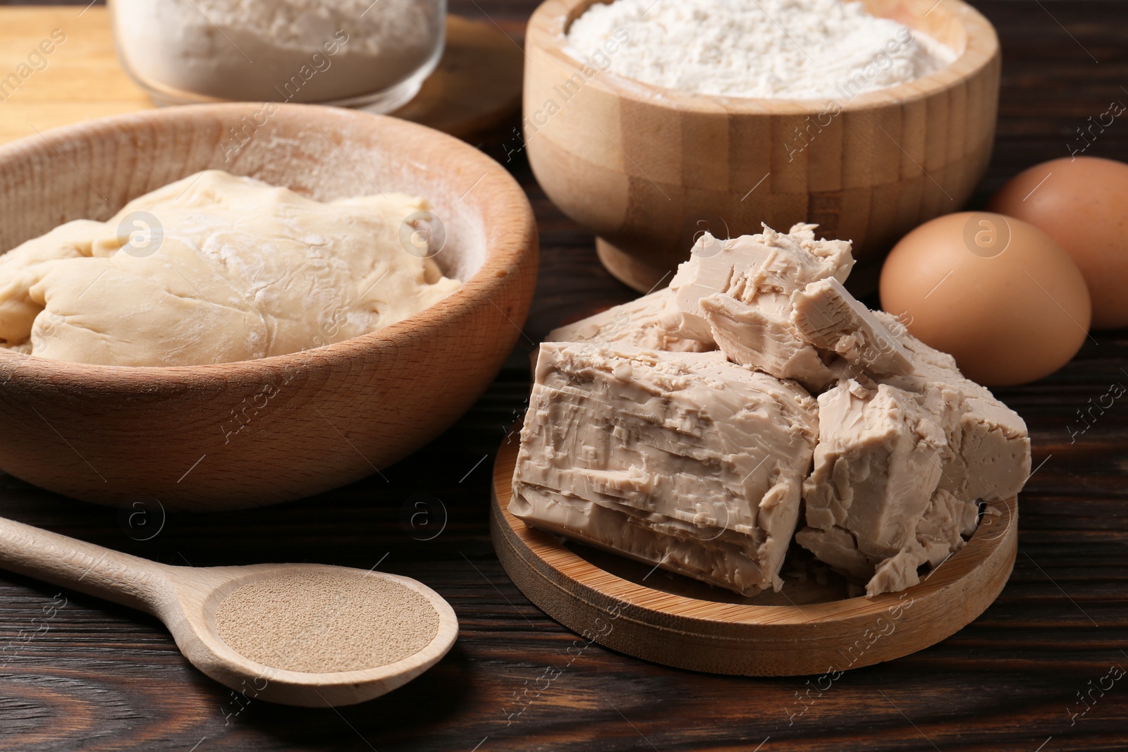 Photo of Different types of yeast, eggs, flour and dough on wooden table