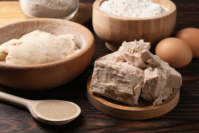 Different types of yeast, eggs, flour and dough on wooden table