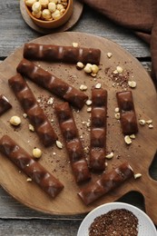 Photo of Tasty chocolate bars with nuts on wooden table, flat lay