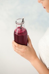 Photo of Woman with bottle of beet smoothie on light background, closeup