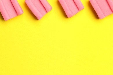 Pink bubble gums on yellow background, flat lay. Space for text