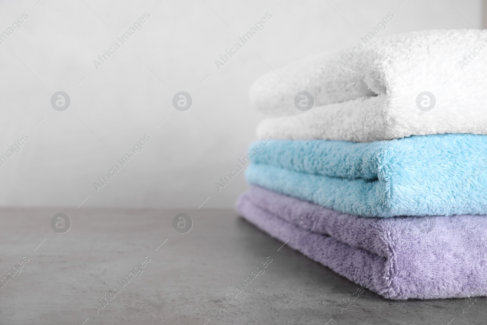 Photo of Stack of clean fresh towels on grey table. Space for text