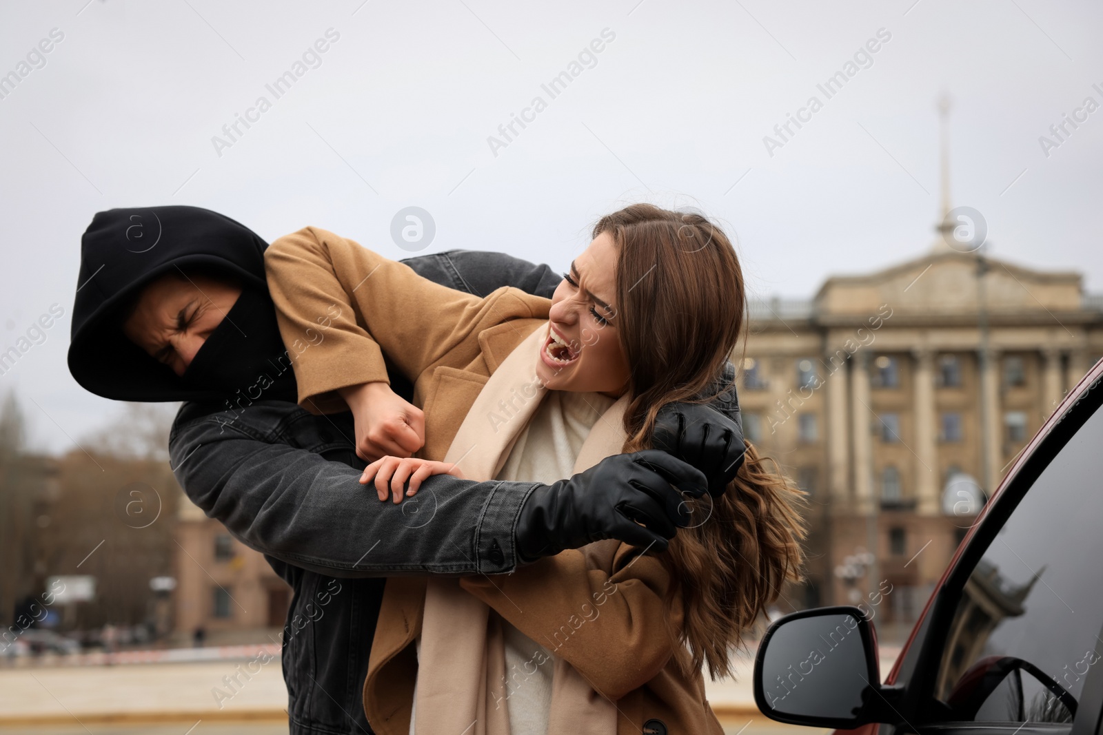 Photo of Woman defending herself from attacker near car outdoors