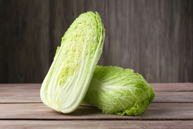 Photo of Whole and cut fresh ripe Chinese cabbages on wooden table