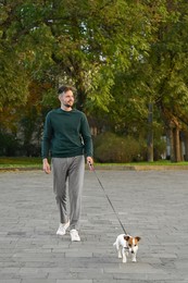 Photo of Man with adorable Jack Russell Terrier on city street. Dog walking