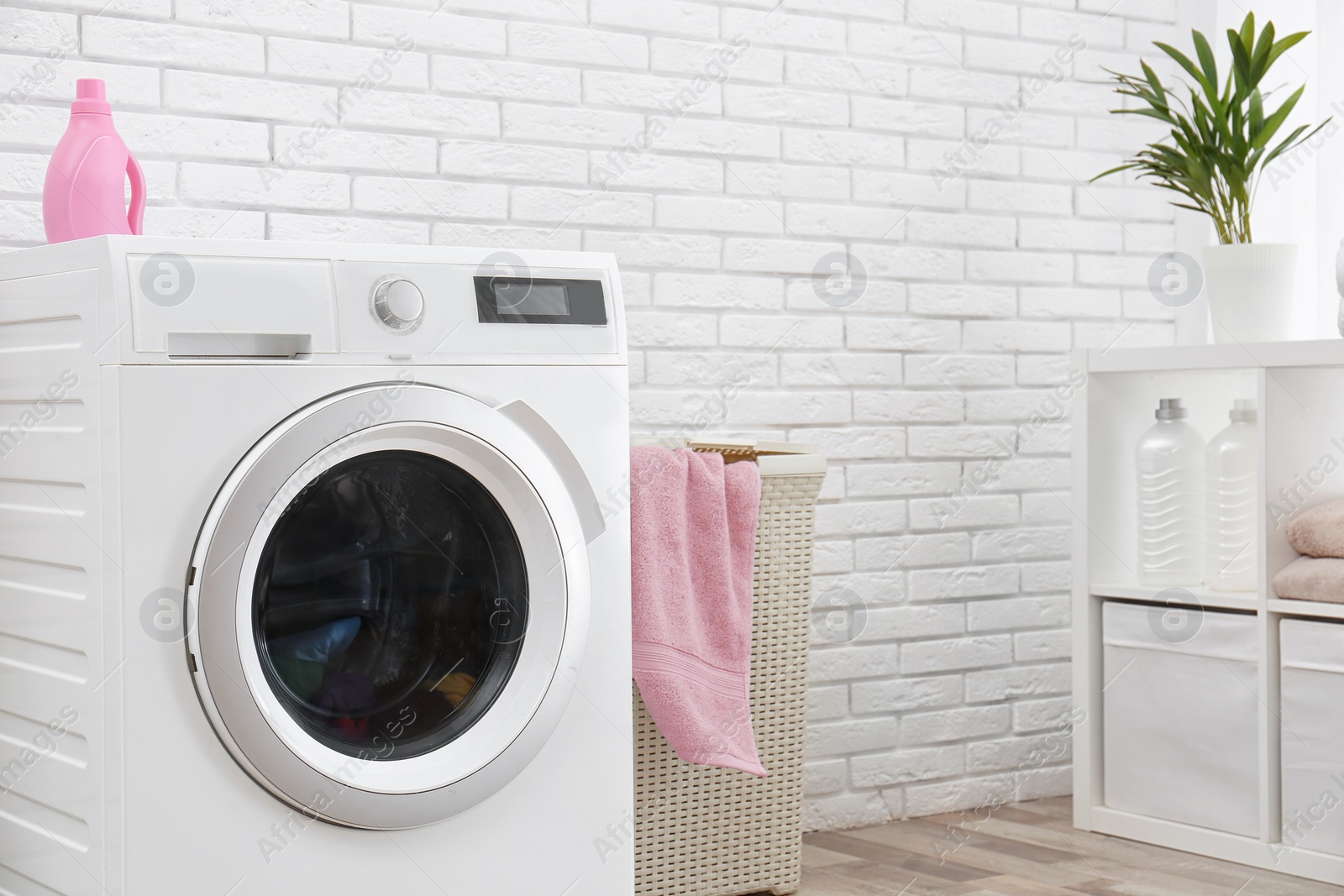 Photo of Modern washing machine near brick wall in laundry room interior, space for text