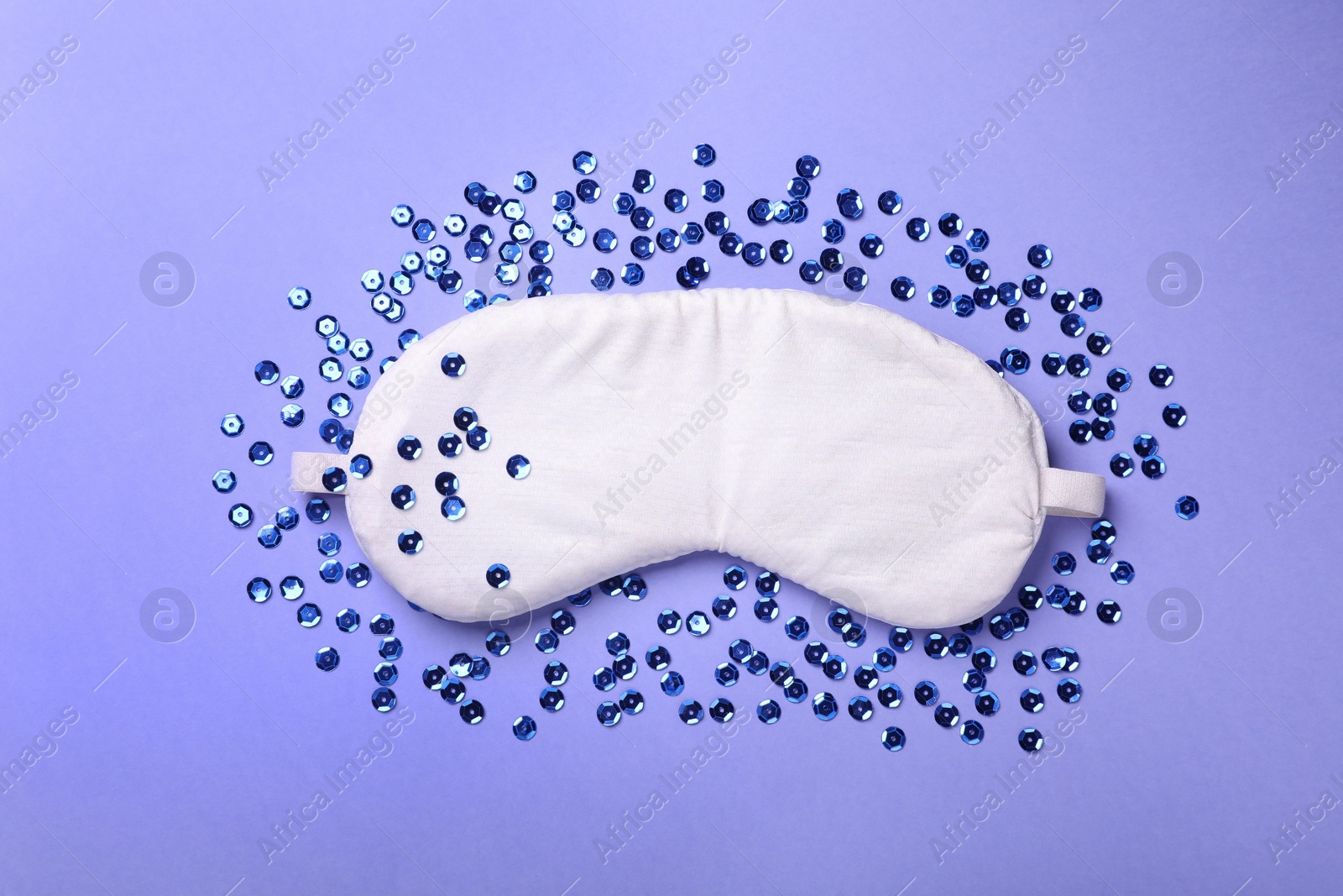 Photo of Soft sleep mask and sequins on blue background, flat lay