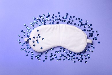 Soft sleep mask and sequins on blue background, flat lay