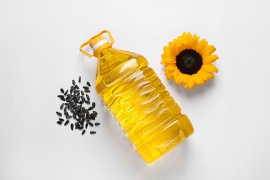 Photo of Bottle of cooking oil, sunflower and seeds on white table, flat lay