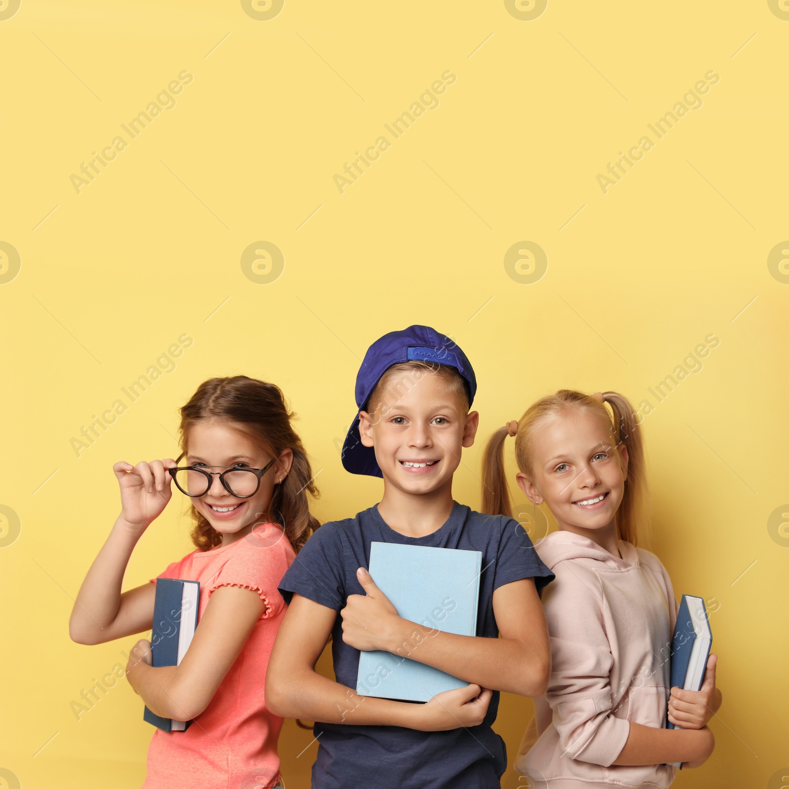 Photo of Little children with books on yellow background. Reading concept