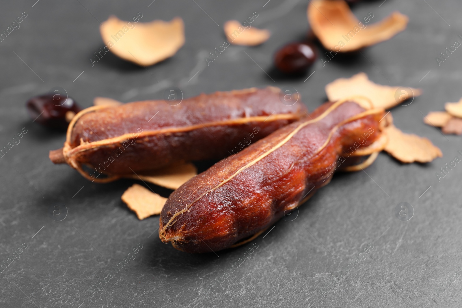 Photo of Peeled tamarind pods on black table, closeup