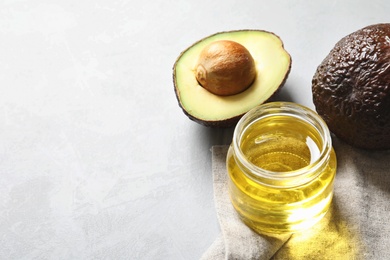 Jar with oil and ripe fresh avocados on table