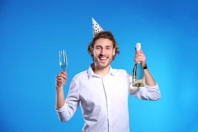 Portrait of happy man holding bottle and glass with champagne on color background