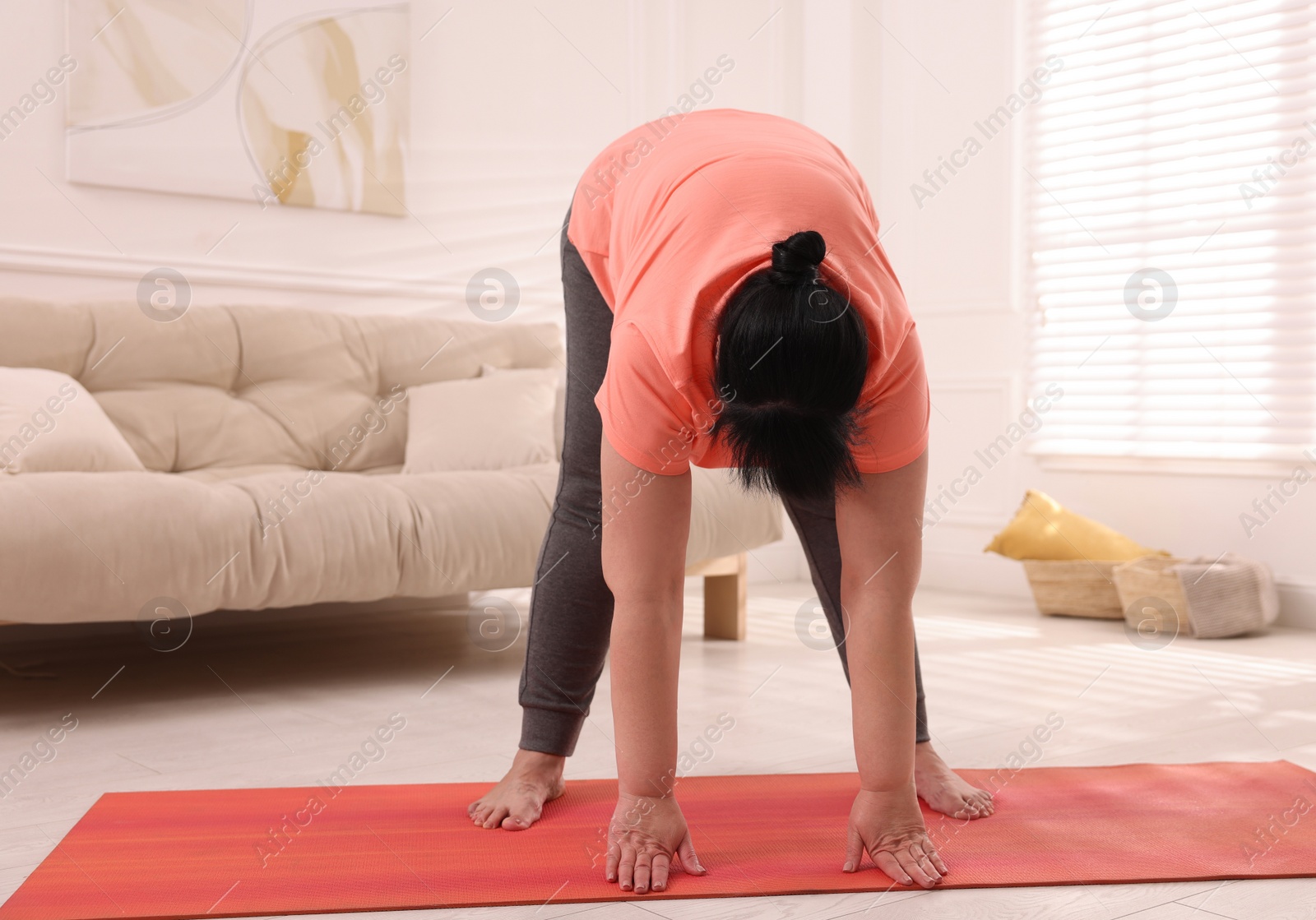 Photo of Overweight mature woman doing exercise on yoga mat at home