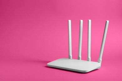 Photo of New white Wi-Fi router on pink background. Space for text