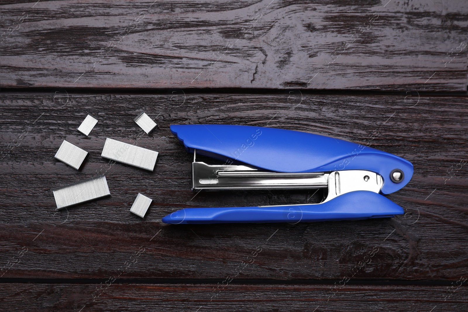 Photo of New bright stapler on wooden table, flat lay. School stationery