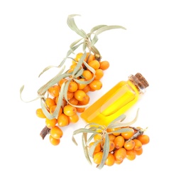 Photo of Natural sea buckthorn oil and fresh berries on white background, top view