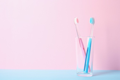 Photo of Cup with toothbrushes on table against color background. Dental care