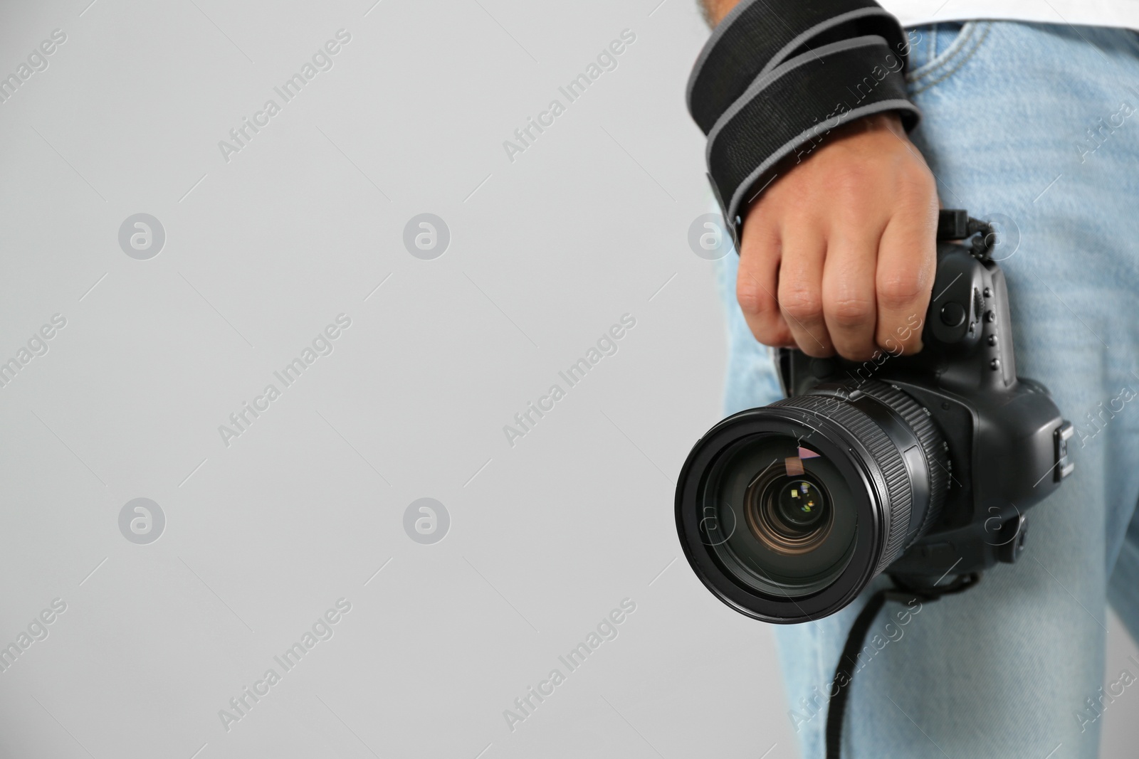 Photo of Professional photographer with modern camera on light grey background in studio, closeup. Space for text