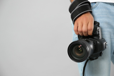 Photo of Professional photographer with modern camera on light grey background in studio, closeup. Space for text