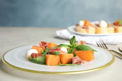 Photo of Fresh melon with prosciutto, mozzarella and basil on table