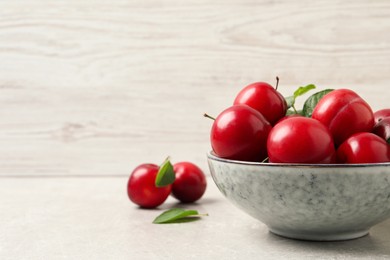 Photo of Delicious ripe cherry plums with leaves on light table. Space for text