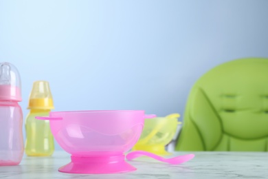 Photo of Plastic bowl and spoon on white marble table indoors, space for text. Serving baby food