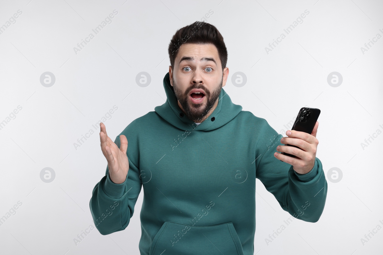 Photo of Shocked young man using smartphone on white background