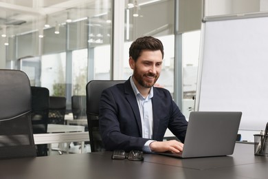 Photo of Man working on laptop at black desk in office
