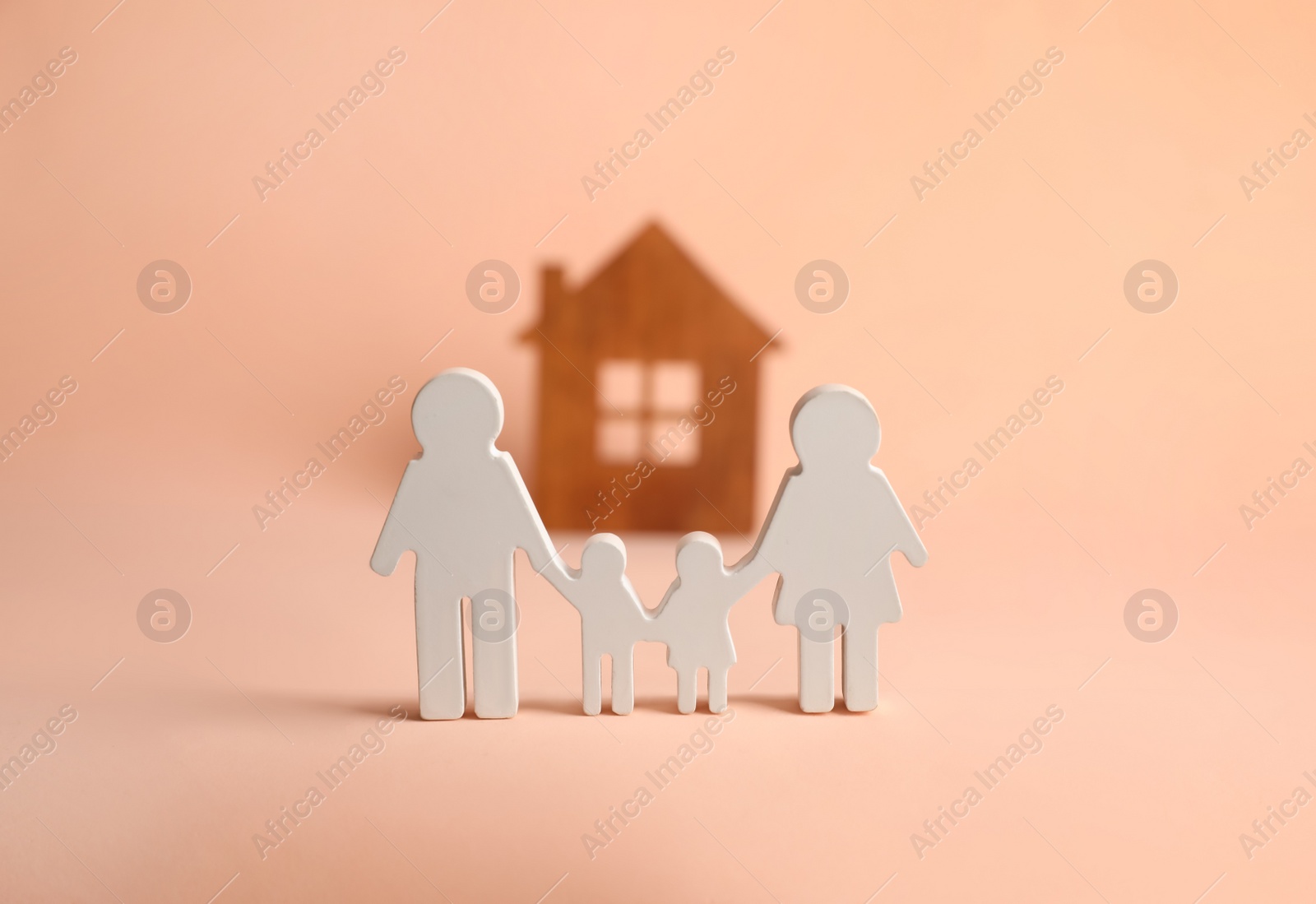 Photo of Figures of family and house on pink background