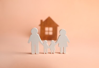 Photo of Figures of family and house on pink background