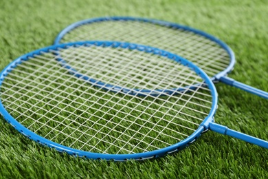 Photo of Badminton rackets on green grass outdoors, closeup