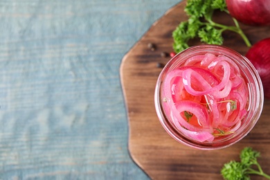 Jar with tasty pickled onions on wooden table, top view. Space for text