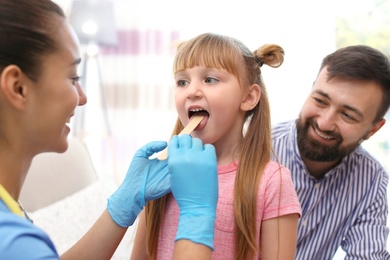 Photo of Children's doctor examining little girl's throat at home